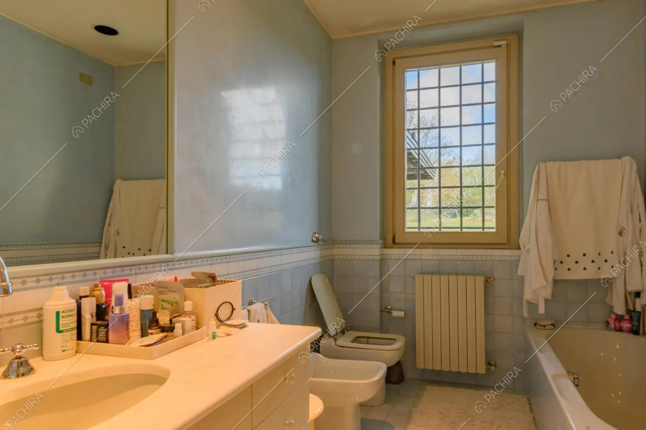 Grande bagno con vasca e piastrelle azzurre su pavimento e pareti