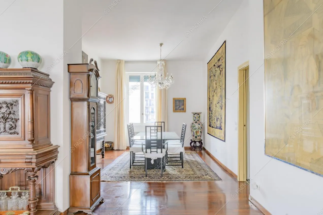 Dal soggiorno vista sulla maestosa sala da pranzo con sedie di design e pavimento in parquet