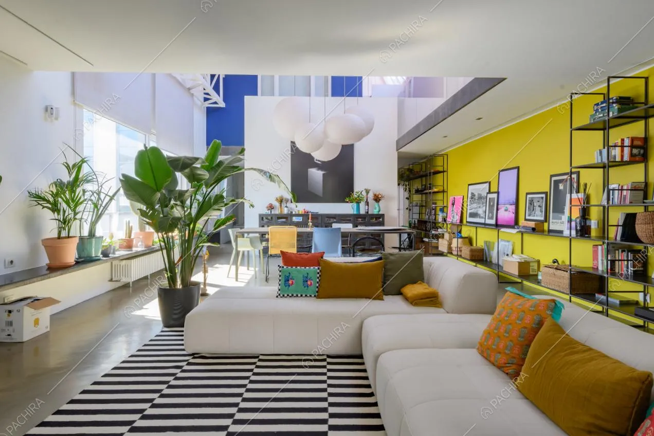 Luminosa zona living con divano bianco angolare e parete gialla con libreria