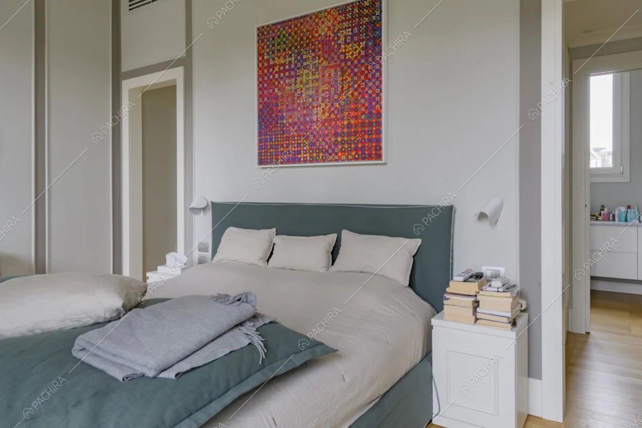 Letto matrimoniale in stanza dalle pareti con boiserie, pavimento in parquet e vista sul bagno