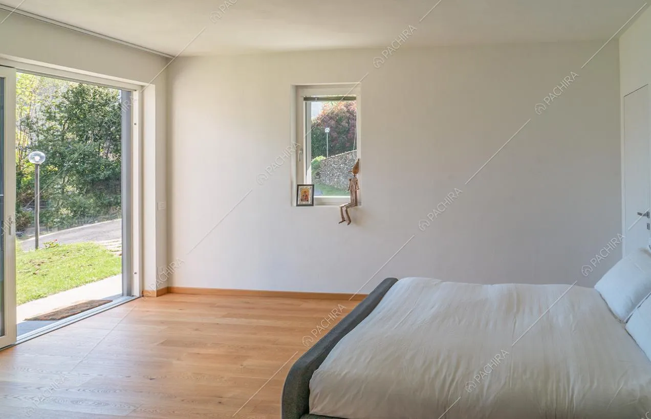 Camera da letto matrimoniale con pavimento in parquet, vista sul lago e porta-finestra per accedere al giardino