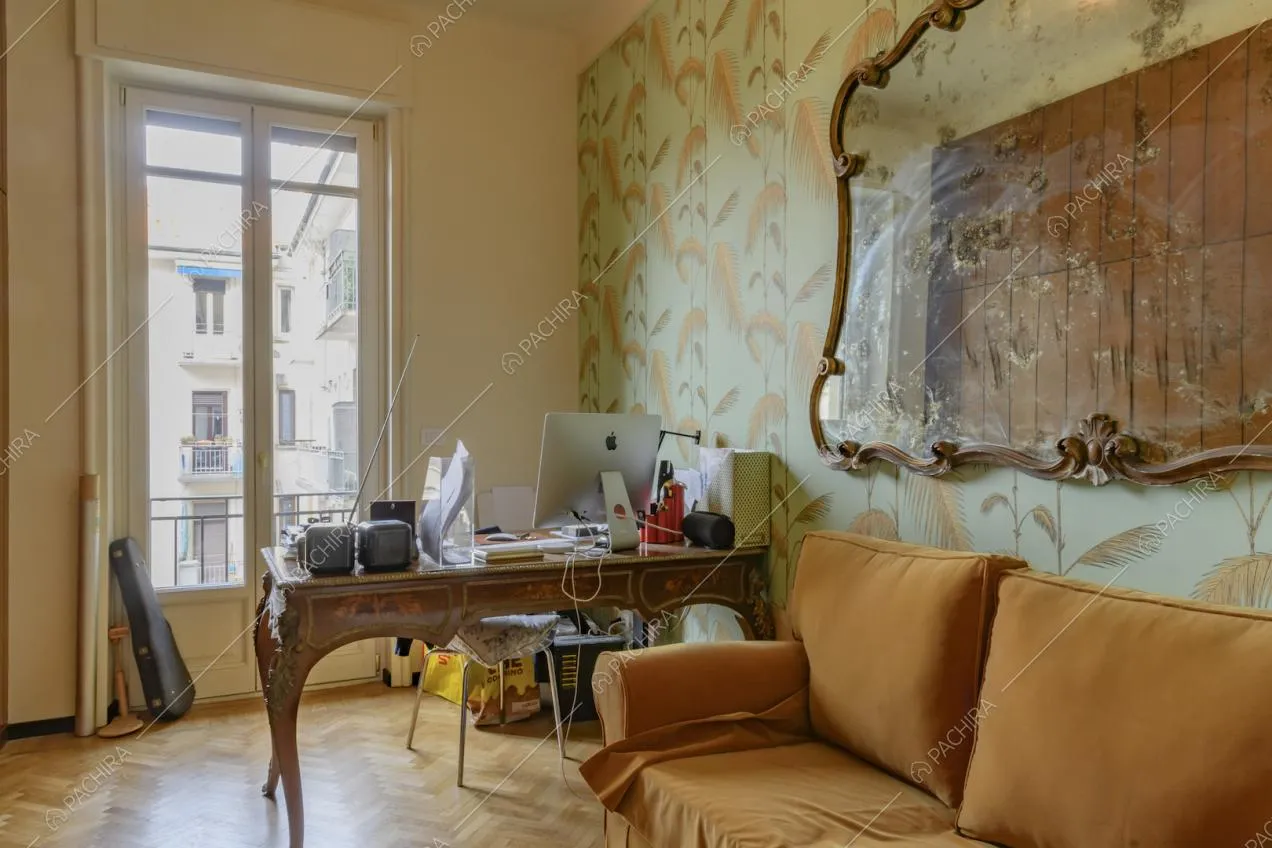 Studio con pavimento in parquet a spina di pesce, carta da parati e divano arancione