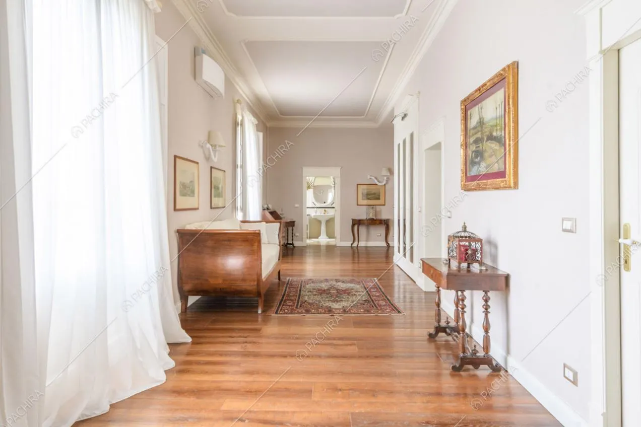 Boiserie sul soffitto nel corridoio con pavimento in parquet e vetrate