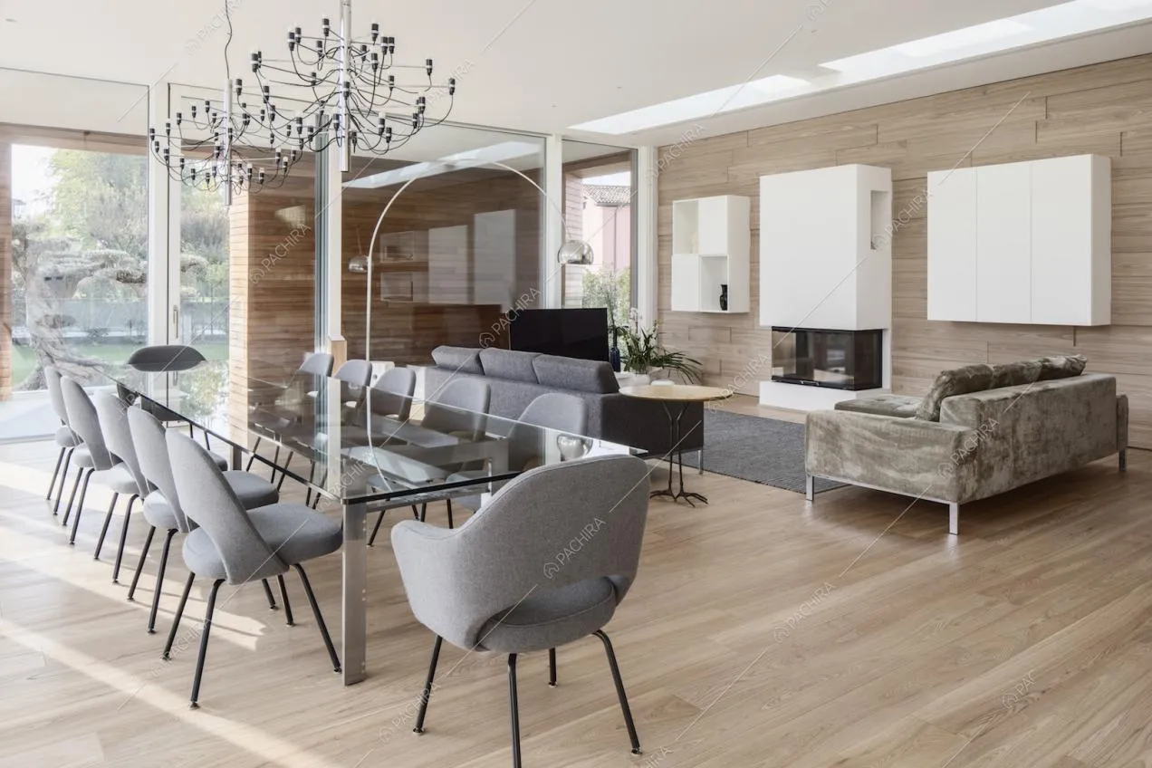 Nel soggiorno con pavimento in parquet e pareti in legno e in vetro, tavolo da pranzo, divani e camino