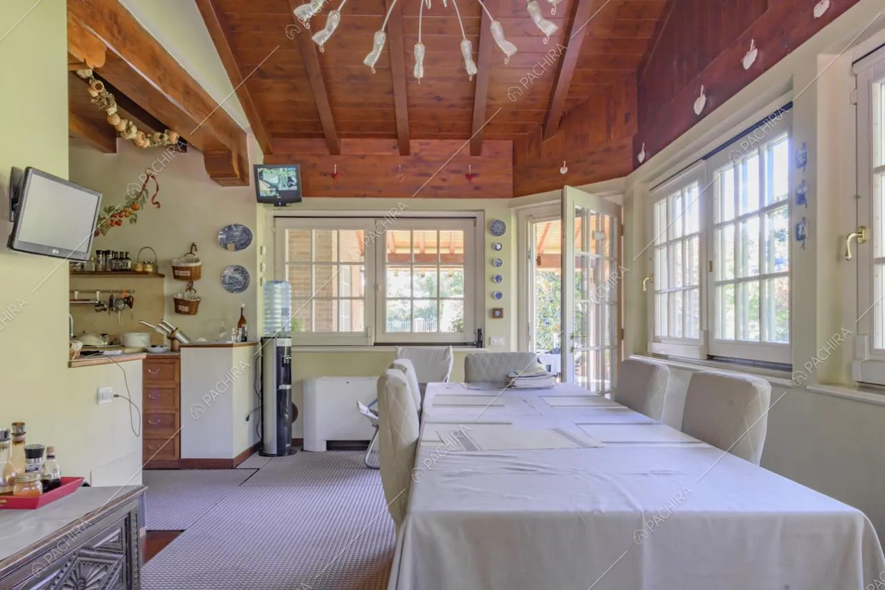 Open space con tavolo, cucina a vista e soffitto in legno