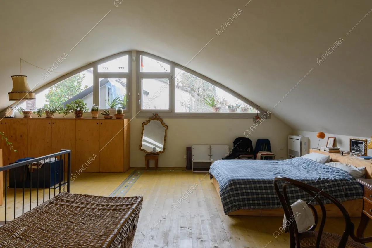 Luminosa camera da letto matrimoniale con vetrata triangolare e pareti bianche