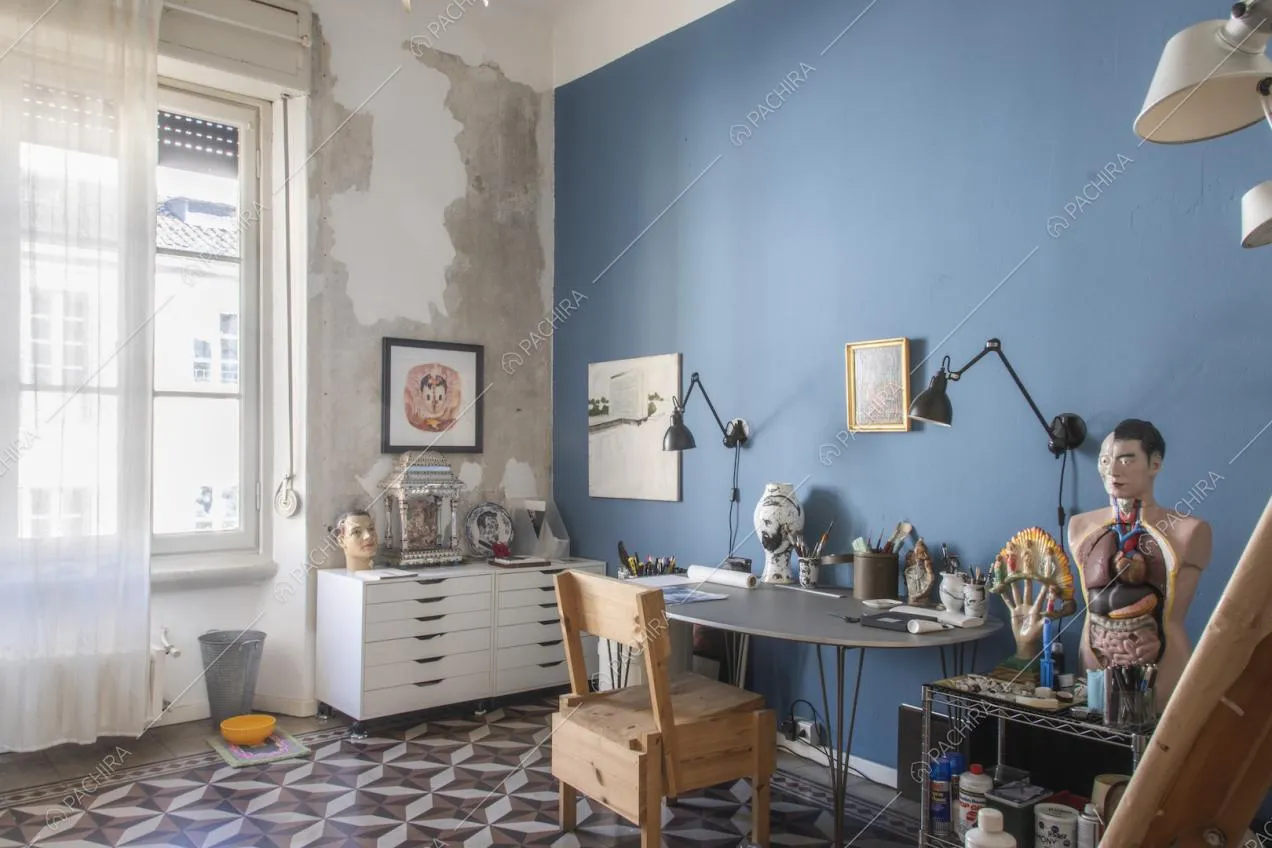 Studio con tavolo ovale, pennelli, lampade da ufficio e cassettiera bianca