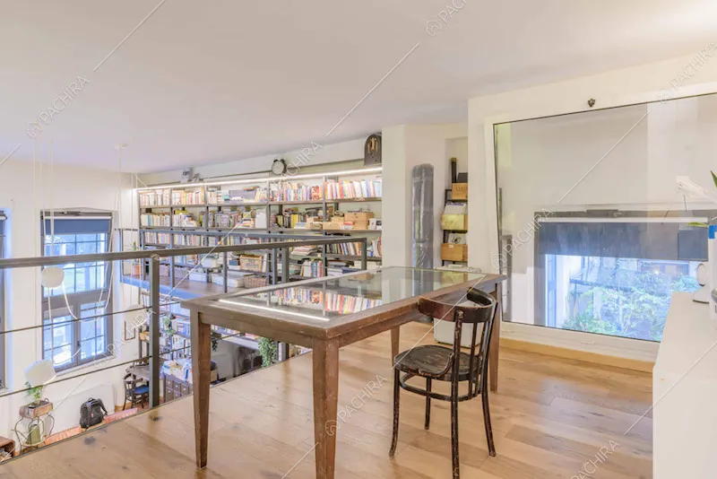 Soppalco con scrivania, pavimento in parquet e vista sul soggiorno con libreria