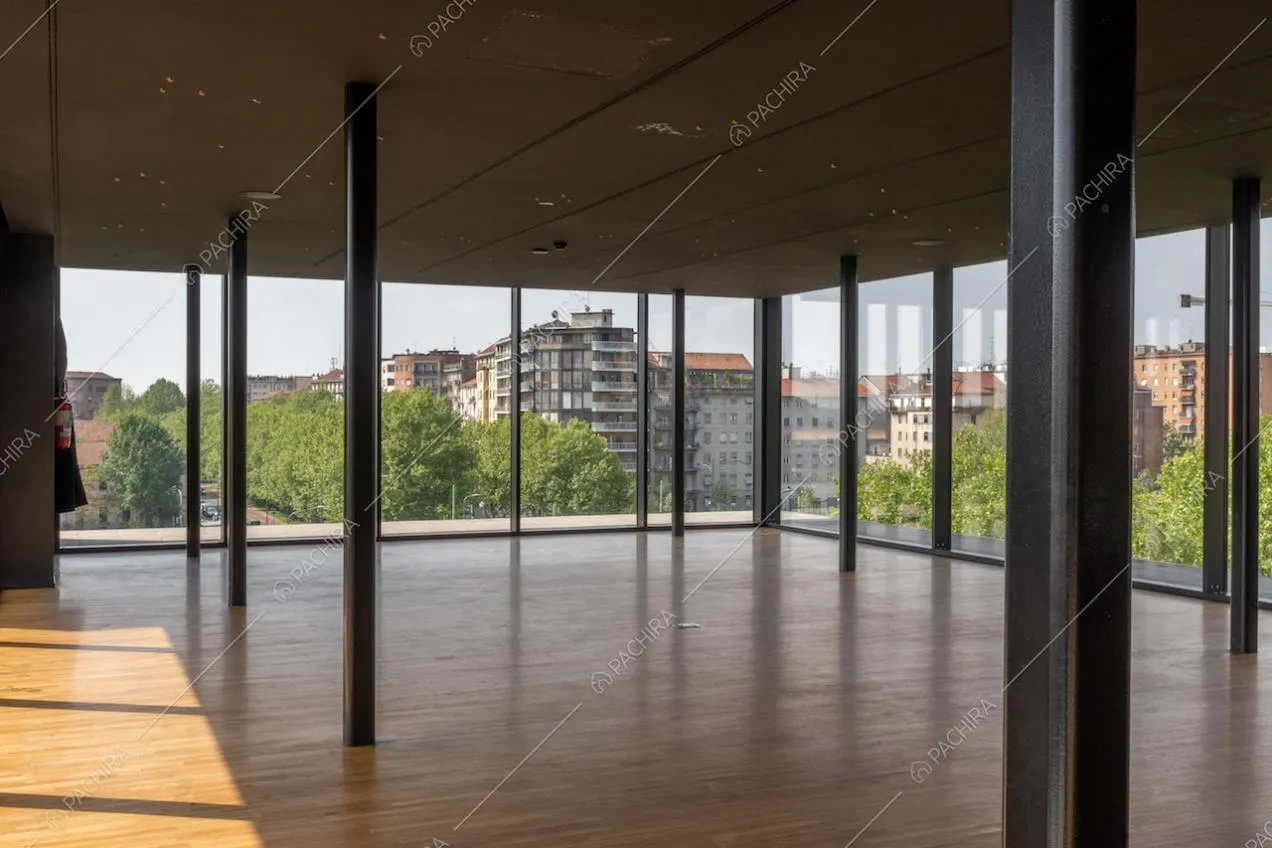 Dall'ampio salone dell'attico con colonne nere in metallo, ampie vetrate e pavimento in parquet, vista su Milano