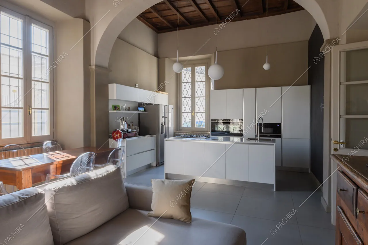 Luminosa zona living con cucina a isola con fornelli a gas e soffitto a cassettoni