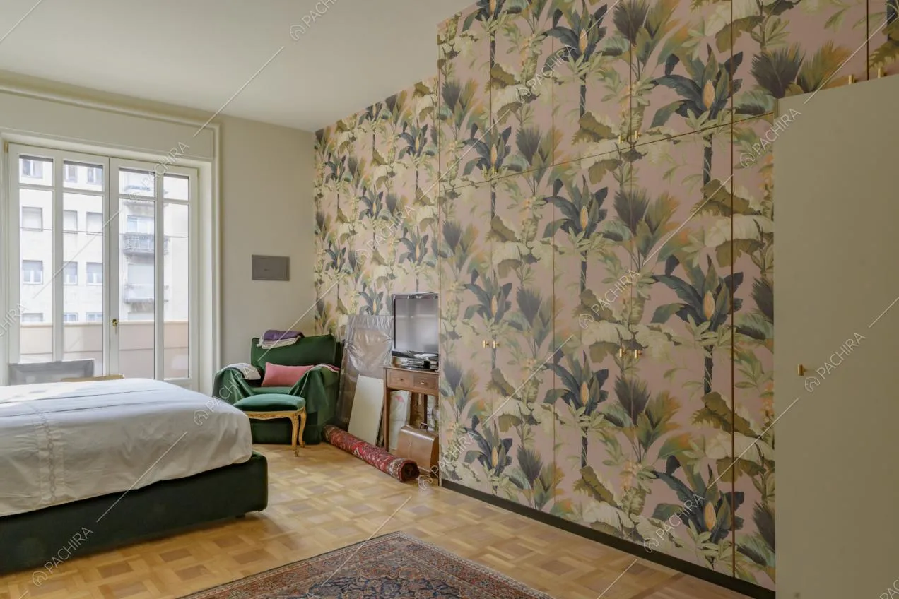 Camera da letto con pavimento in parquet, carta da parati sull'armadio a muro e porta-finestra