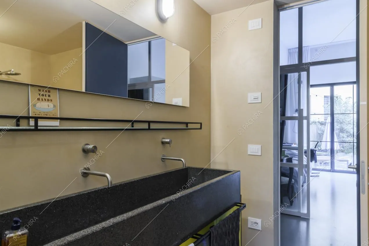 Bagno con lavandino a tre posti nero e vista su camera da letto
