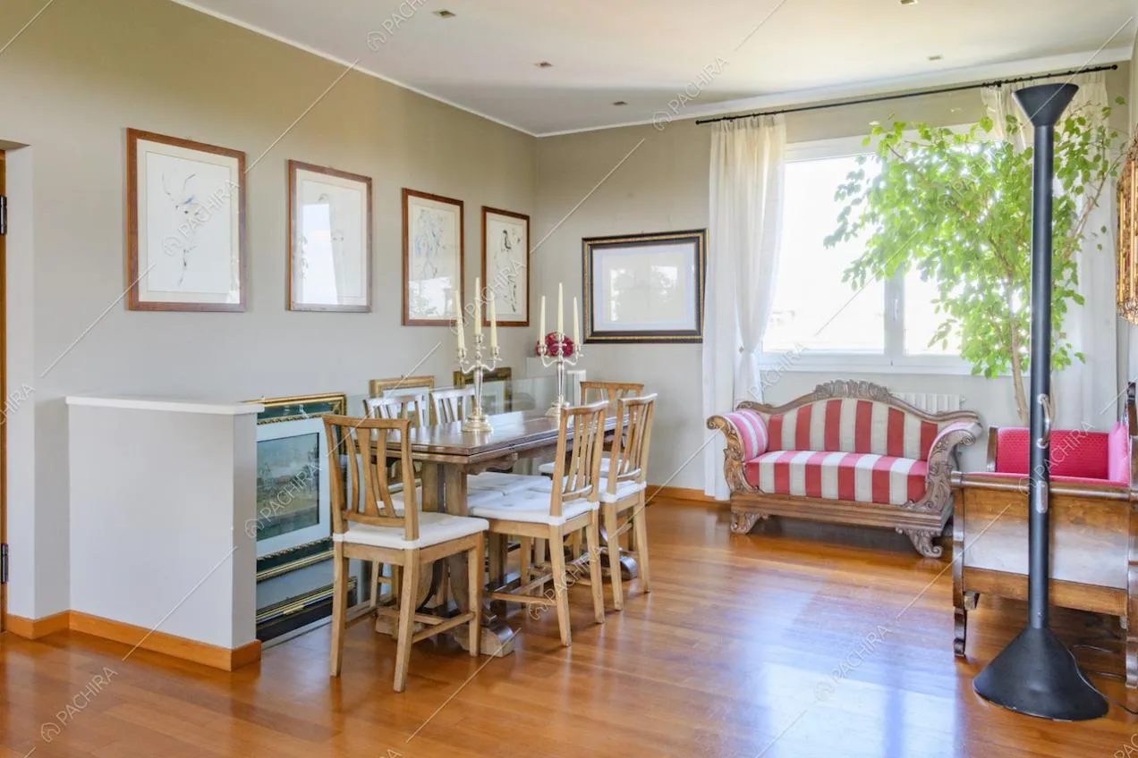 Candelabri sul tavolo da pranzo, divano a righe e quadri alle pareti