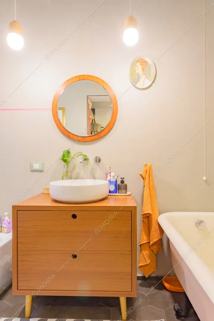 Mobile di legno nel bagno con pareti bianche, pavimento in cementine grigie e vasca