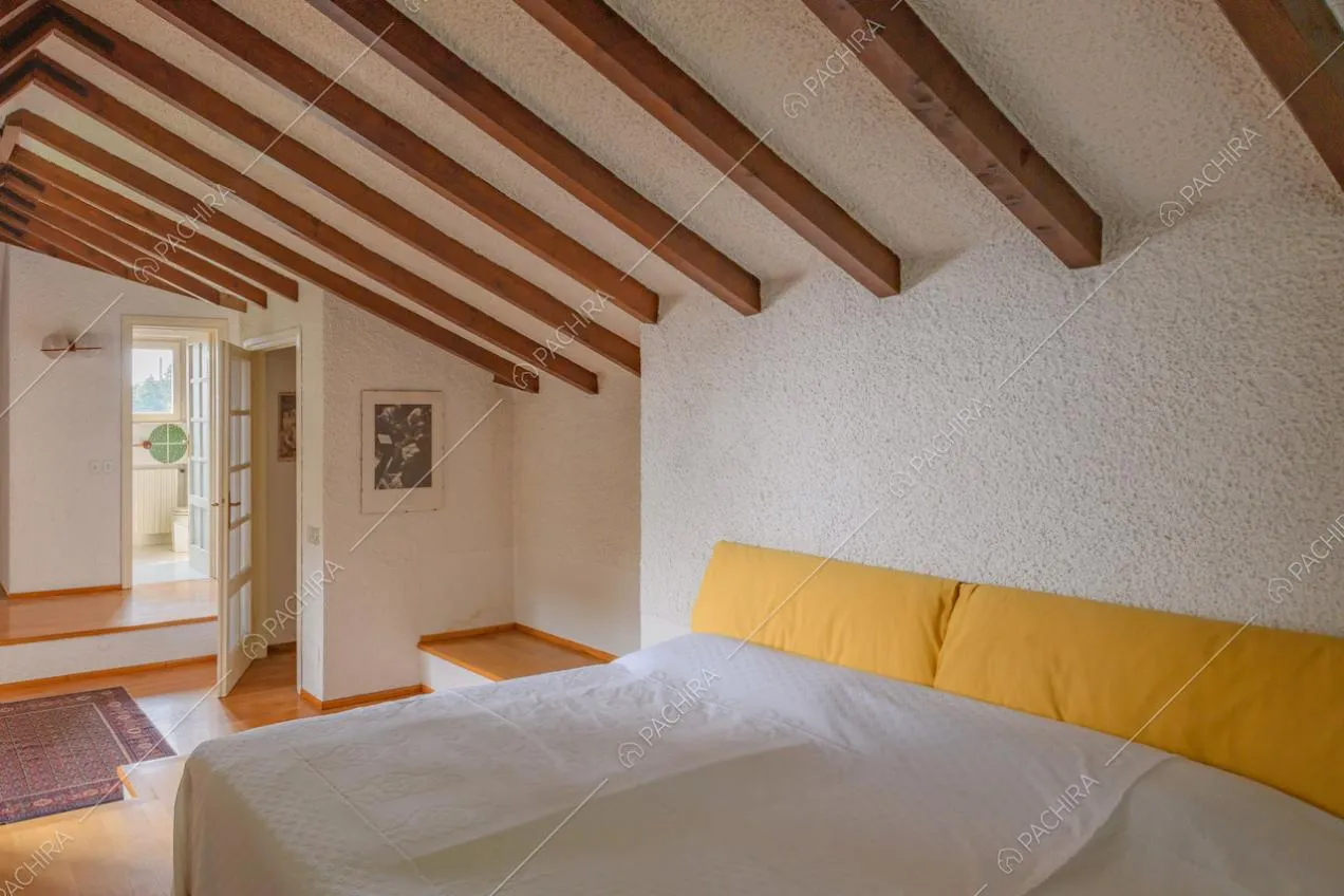 Letto matrimoniale nella camera con pavimento in parquet e pareti bianche