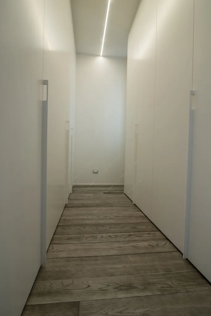Corridoio con mobili bianchi e parquet a listoni