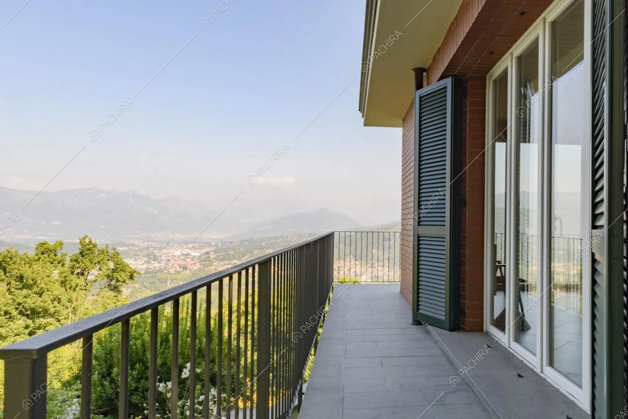 Balcone con ringhiera, porte-finestre e vista panoramica sulle montagne