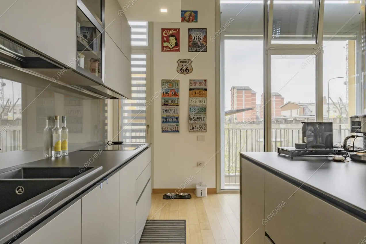 Cucina a isola con fornelli a induzione e porte-finestre per accedere al balcone