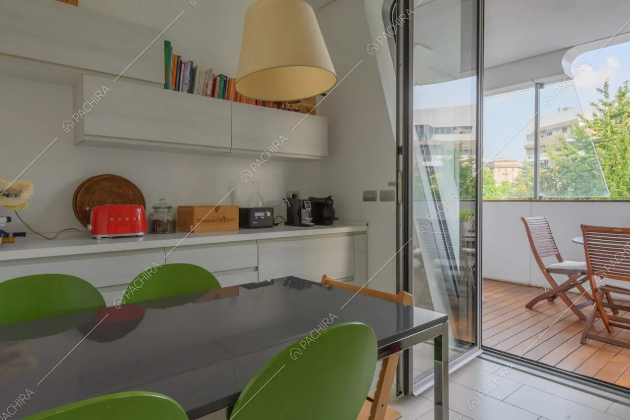 Cucina bianca a parete con tavolo da pranzo e porta-finestra per accedere alla terrazza