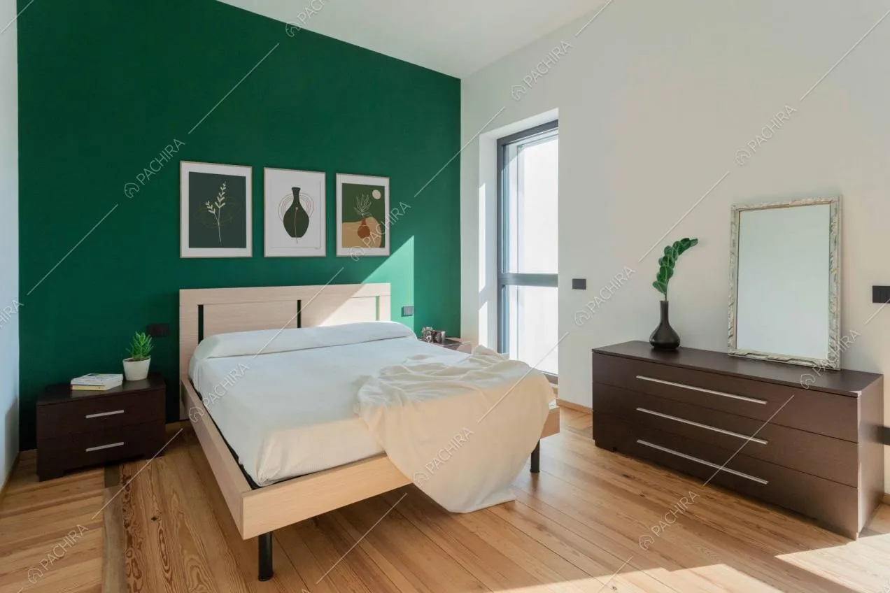 Camera da letto matrimoniale dal pavimento in parquet e dalle pareti verde e bianca