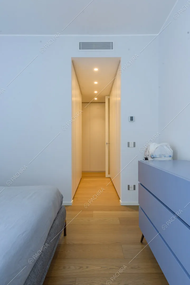 Letto matrimoniale grigio nella camera con pareti bianche e pavimento in parquet
