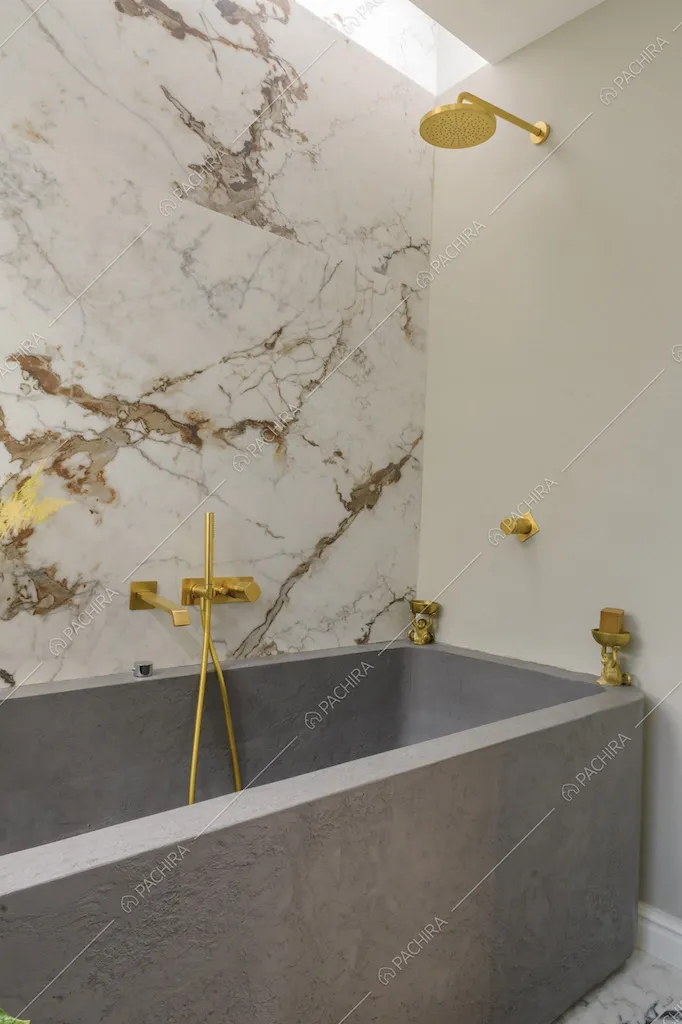 Vasca da bagno grigia con rubinetteria dorata e parete in marmo