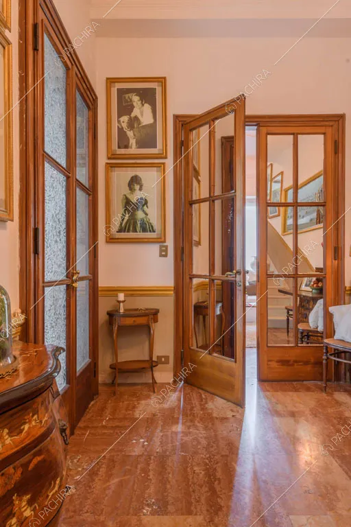 Porte a vetri in legno nell'atrio con mobilio antico e pavimento in graniglia