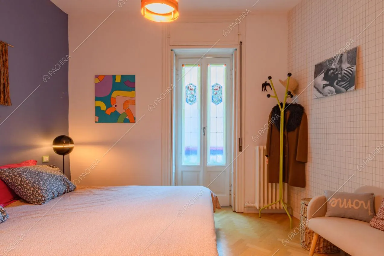 Parete in piastrelle bianche e pavimento in parquet a spina di pesce nella camera da letto matrimoniale