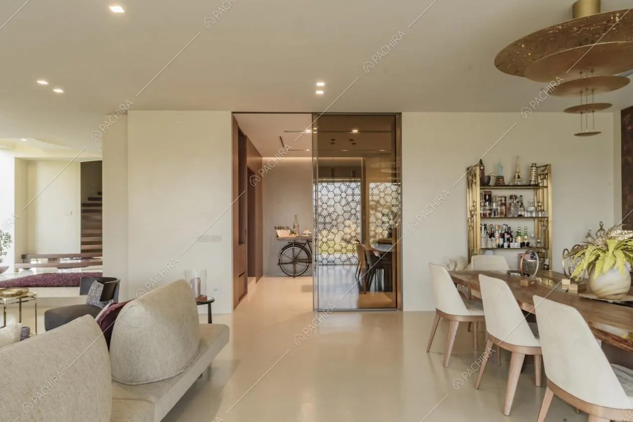 Ampia sala da pranzo con accesso alla cucina tramite porta scorrevole e lampadario di design sopra al tavolo da pranzo