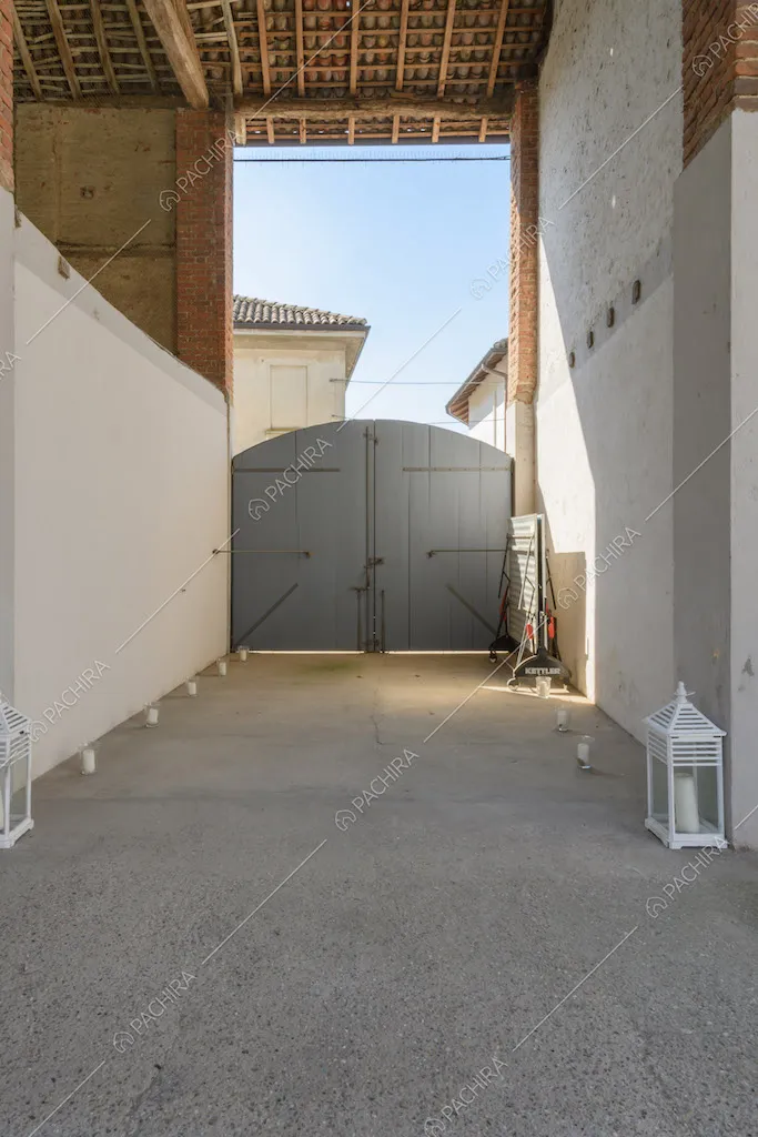 Cancello d'ingresso, pareti bianche e soffitto in legno a vista