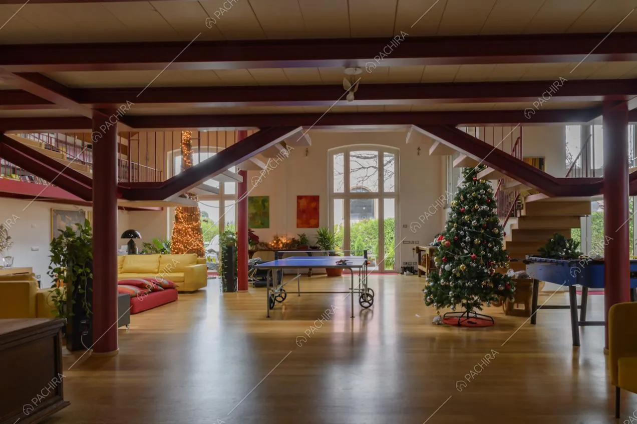 Vista sull'ampio salone con pavimento in parquet illuminato dalle grandi vetrate