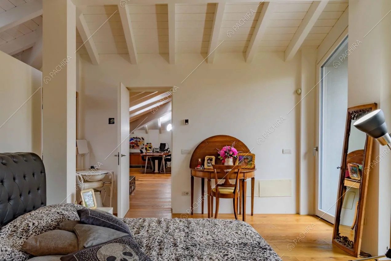 Camera da letto matrimoniale con pavimento in parquet, vetrate e vista sullo studio
