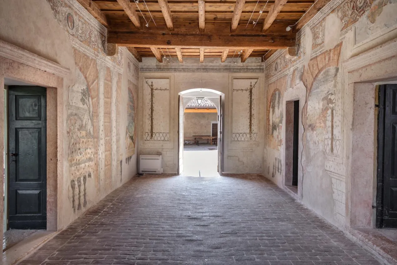 Corridoio con pareti affrescate, pavimento in cotto e soffitto in travi in legno a vista