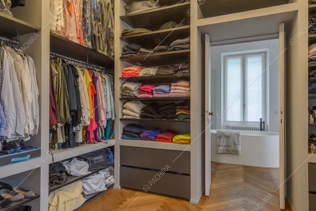Cabina armadio con pavimento in parquet a spina di pesce e vista sul bagno privato