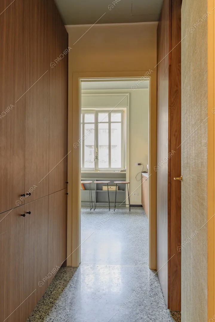 Corridoio con armadio a muro, pavimento in marmo e vista sugli sgabelli della cucina
