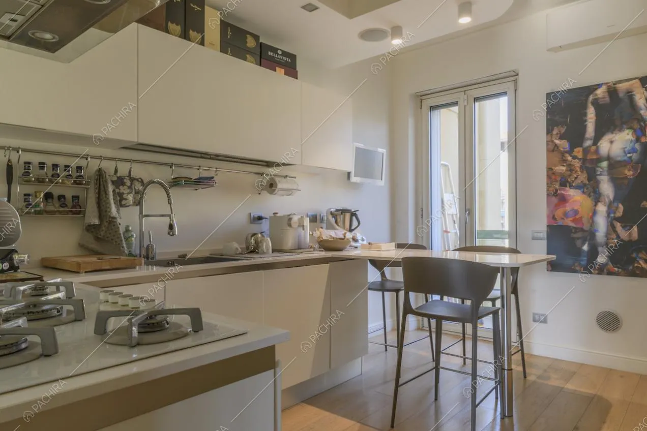 Cucina bianca con fornelli a gas e portafinestra