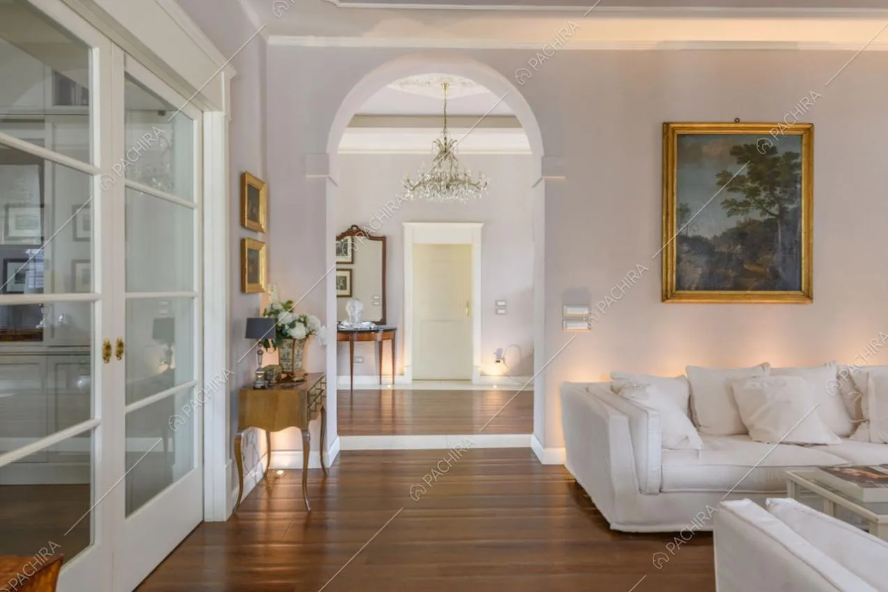 Pavimento in parquet nella zona living con arco, porta a vetri e divani bianchi