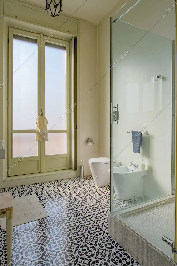 Ampio bagno con pavimento in piastrelle nere e bianche e box doccia con pareti in vetro