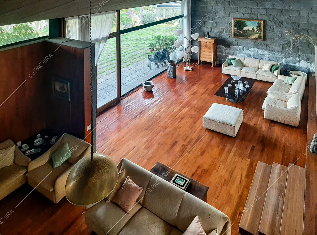 Vista dall'alto sulla zona living con divani bianchi, pavimento in parquet e parete vetrata