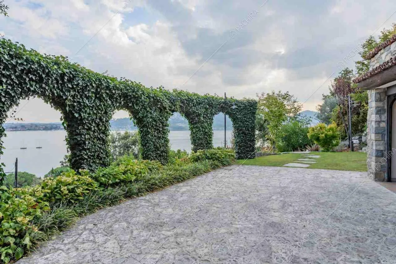 Pavimentazione in lastre di pietra sulla terrazza con vista sul lago e archi ricoperti di rampicanti