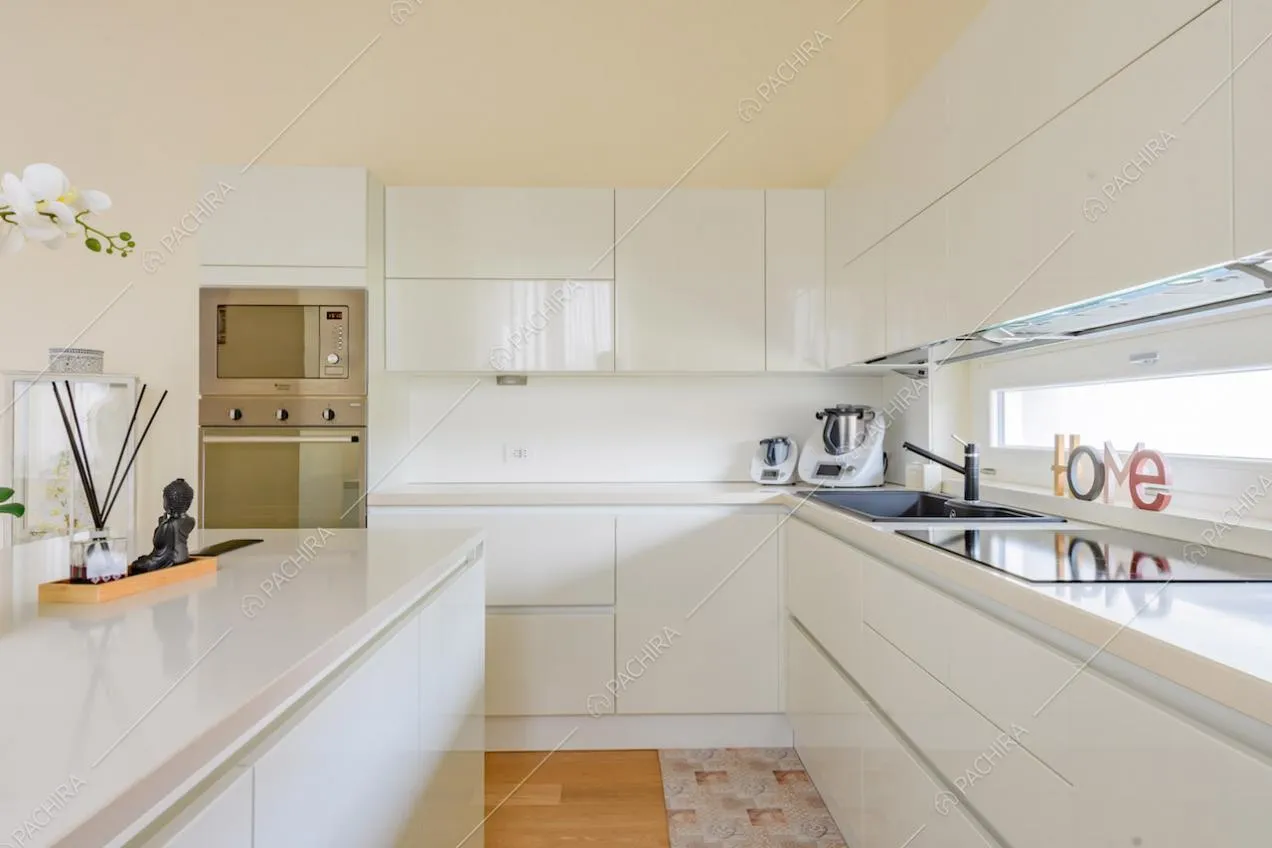 Fornelli a induzione nella luminosa cucina bianca con isola e pavimento in parquet