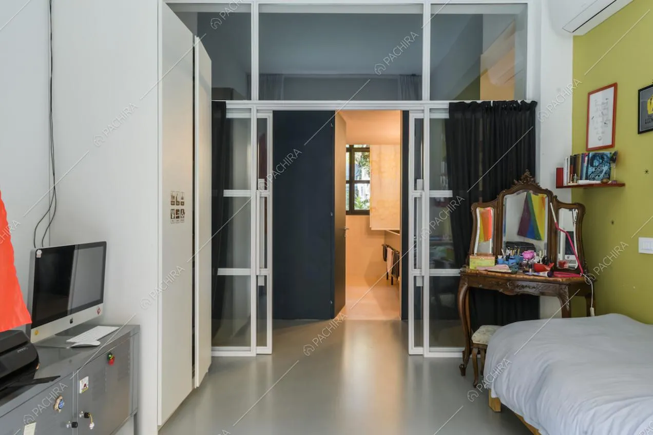 Camera da letto con pavimento in resina, parete verde e vista sul bagno