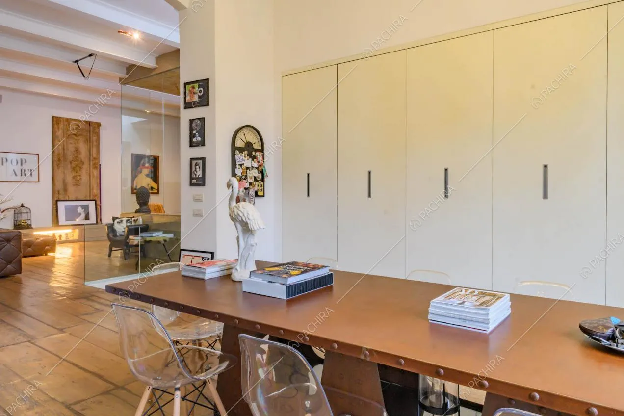 Tavolo da pranzo marrone nella cucina con armadi bianchi a muro e pavimento in parquet