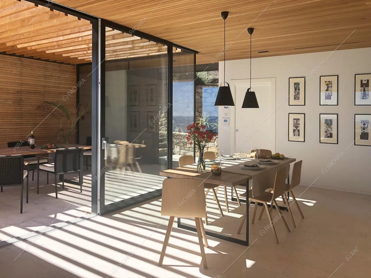 Veranda con soffitto in travi in legno a vista, separata dalla cucina dalle porte-finestre scorrevoli