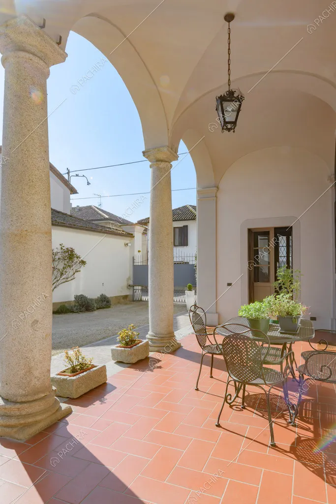 Vista sul giardino dal portico con soffitto a volte a crociera e tavolino da esterni