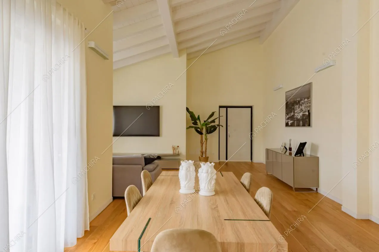 Tavolo da pranzo nella zona living con vetrate, pareti gialle e travi a vista