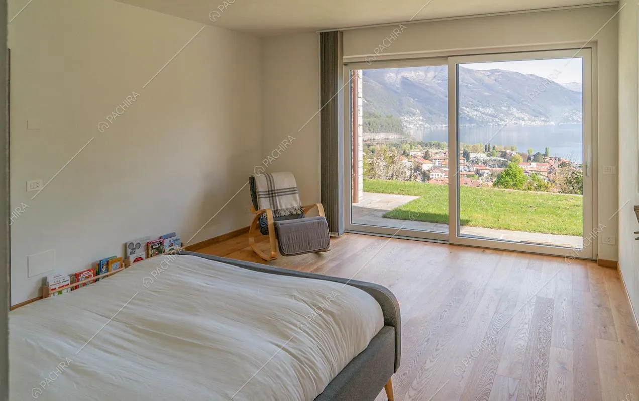 Camera da letto matrimoniale in stile minimal con vista sul lago dalla porta-finestra
