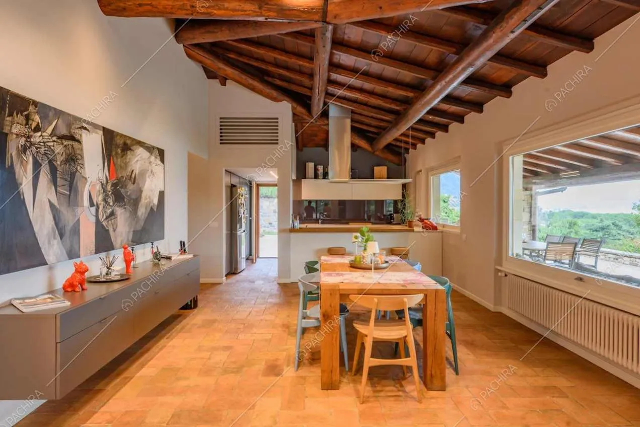 Open space con pavimento in cotto, soffitto in travi in legno a vista e cucina a parete
