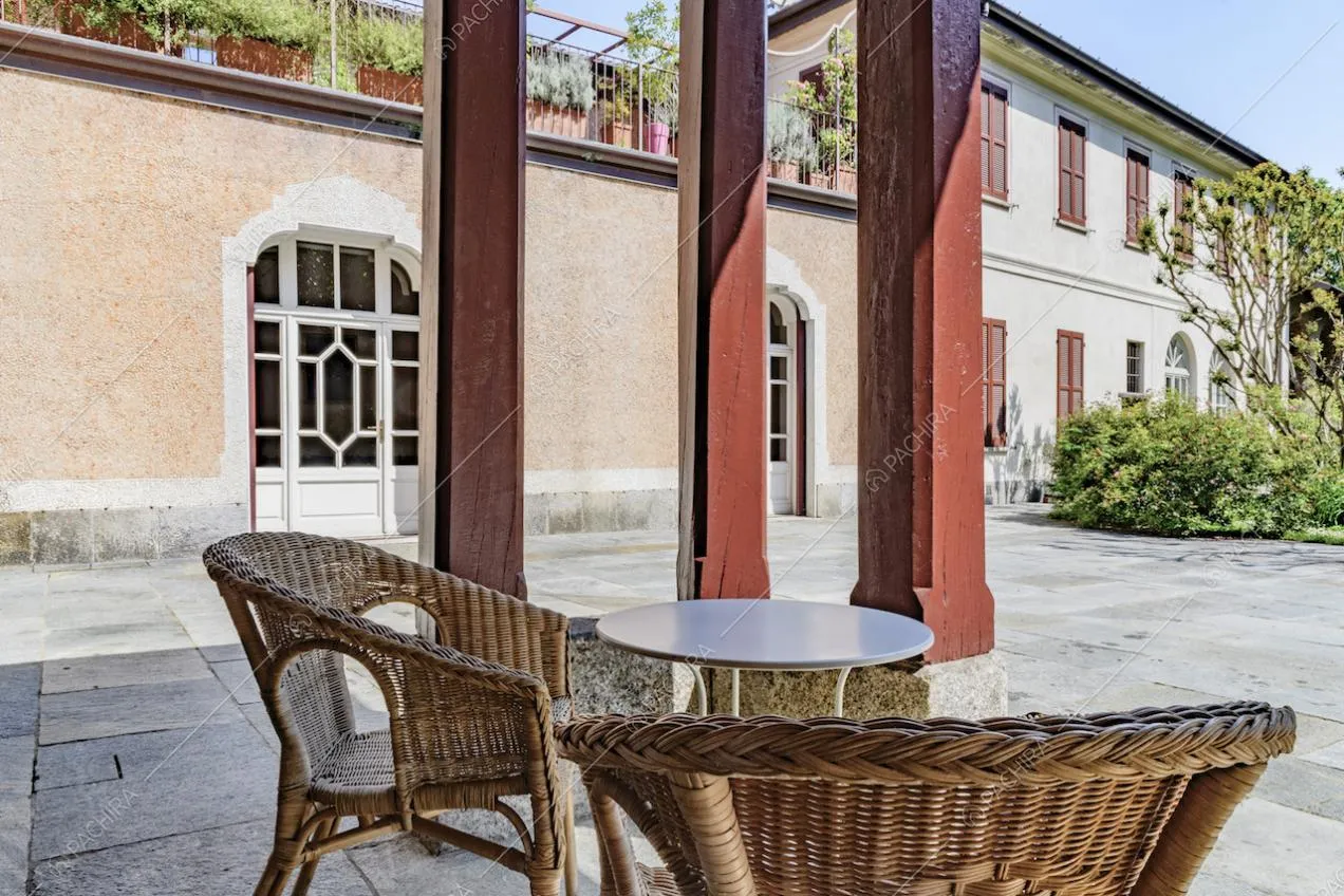 Nel cortile d'ingresso salottino da esterno con colonne rosse e vista sulla terrazza del primo piano