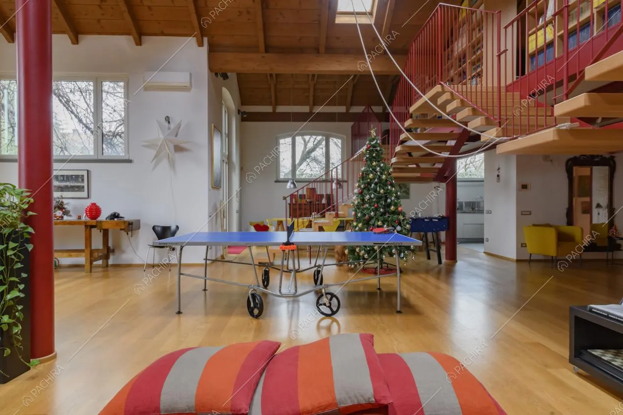 Dal pouf rosso vista su tutto il salone con pavimento in parquet e soppalco con scala che sale e scende